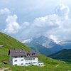 Die Valentini-H&uuml;tte am Sellajoch, darunter das Fassatal mit dem Marmolada-Gletscher als Kulisse. Foto: AT, &copy; Peer